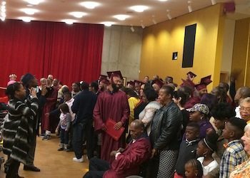 Families and friends join the graduates on the stage to take a group photo. (Briahnna Brown/HU News Service)