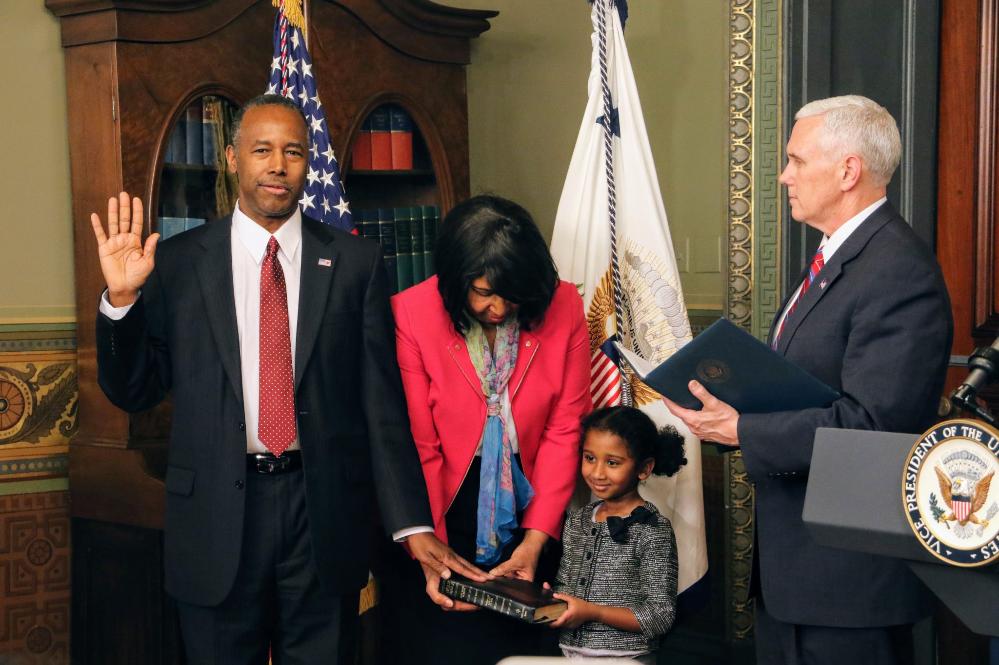 Ben Carson (left) is sworn in by Vice President Mike Pence as the Trump administration's secretary of Housing and Urban Development in the Eisenhower Executive Office Building on the White House complex on March 3, as his wife Candy and 5-year-old granddaughter, Tesora, hold the Bible. (Shevry Lassiter/The Washington Informer)