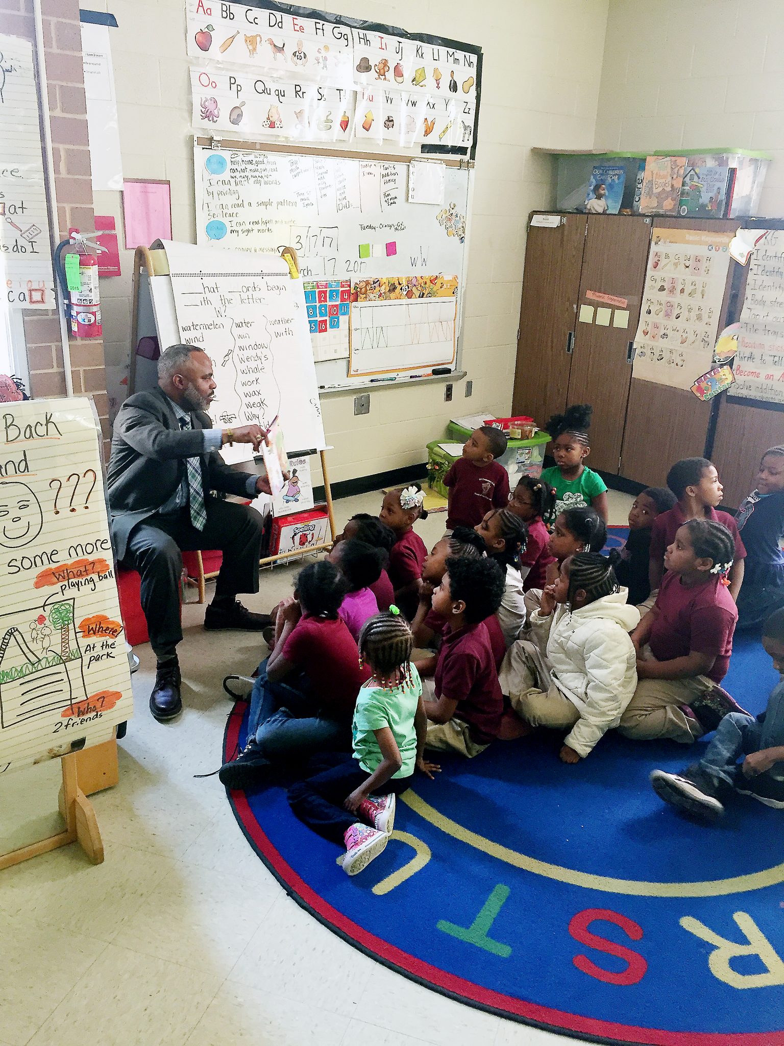 Kelly Gilmore, member of the Omicron Lamda Alpha chapter of Alpha Phi Alpha Fraternity Inc, reads to a class of first-graders at Orr Elementary School in Southeast after the organization donated over 300 books to its library on March 17. (Courtesy photo)