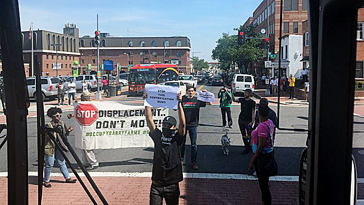 Protesters with Empower D.C. block a bus tour of developers speculating in Anacostia on April 19. (Courtesy of The Washington Business Journal)