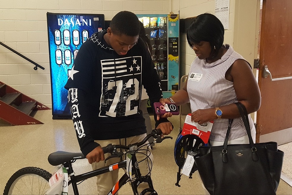 Daniel Pearson (left), a seventh-grader at Dwight D. Eisenhower Middle School in Laurel, Maryland, and his mother, Josephine Dallas, look at one of the new bicycles and helmets given by a local auto dealership during a June 8 school assembly as rewards to Pearson and fellow classmates for maintaining perfect attendance throughout the 2016-17 school year. (William J. Ford/The Washington Informer)