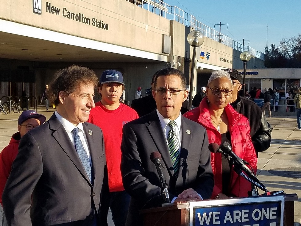 Maryland Reps. Anthony Brown (at podium) and Jamie Raskin present legislation they say will improve Metro during a Nov. 28 press conference outside the New Carrollton Metro station. Amalgamated Transit Union Local 689 President Jackie Jeter (right) also spoke during the conference. (William J. Ford/The Washington Informer)