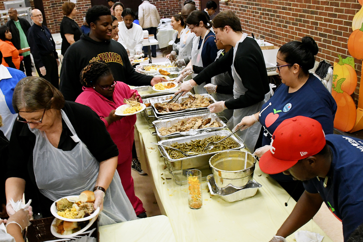 Volunteers with Children of Mine Youth Center, Inc., Our Lady of Perpetual Help Catholic Church and Martha's Table partner on Nov. 18 to serve Thanksgiving dinner at the Panorama Room in southeast D.C. (Roy Lewis/The Washington Informer)