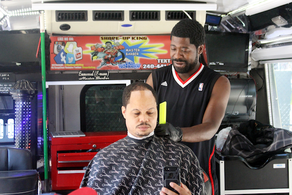 Emmanuel "E-Man" Azoro, also known as "The Shapeup King," tends to a customer inside his mobile barbershop during the second annual Man Cave at Emery Heights Father's Day Celebration on June 16. (Courtesy of Man Cave at Emery Heights)