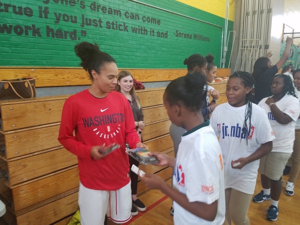 Washington Mystics point guard Kristi Toliver hands a mouthguard to a youth during a Jr. WNBA basketball clinic at Charles Hart Middle School in southeast D.C. on Sept. 11. (William J. Ford/The Washington Informer)