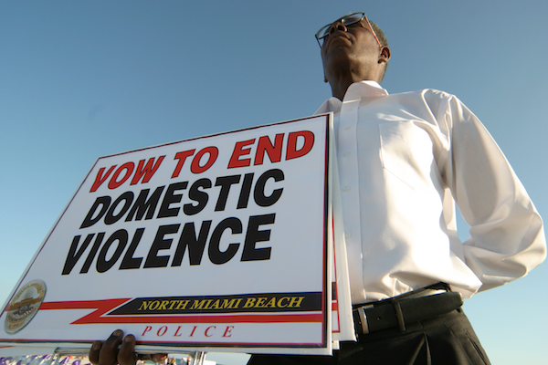 A man holding a sign at the Domestic Violence March event. (Photo by: Jeffrey Greenberg/UIG via Getty Images)