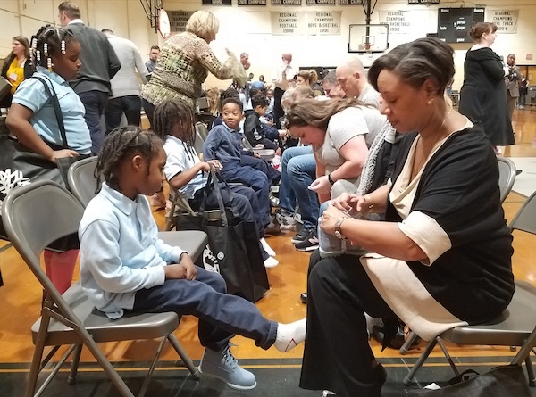 Prince George's County Public Schools interim CEO Monica Goldson (right) laces up an ice-blue Timberland boot for Brylin Hutchins, 5. Timberland donated 400 pairs of boots to every student at District Heights Elementary on Oct. 31. (William J. Ford/The Washington Informer)