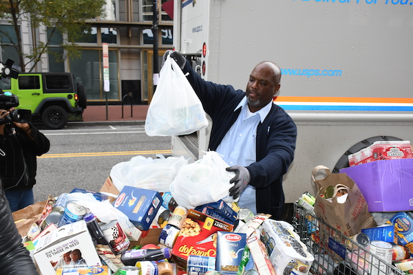 U.S. Postal Service employee Cecil Rich leaves donations at the NBC4 Food for Families drop-off area while on his mail delivery route in northwest D.C. on Nov. 19. (Roy Lewis/The Washington Informer)