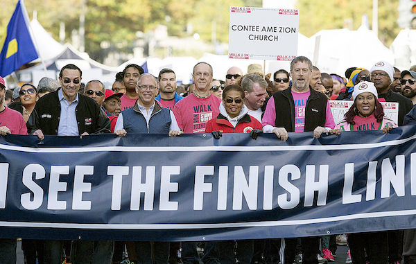 D.C. Councilman Vincent Gray, Walk Grand Marshall Jim Obergefell, Rep. Eleanor Holmes Norton, Whitman-Walker Executive Director Don Blanchon and Bishop Allyson Abrams of Empowerment Liberation Cathedral hold the "We Can See the Finish Line" banner at the 2017 Walk & 5K to End HIV. (Photo by Edward Le Poulin)