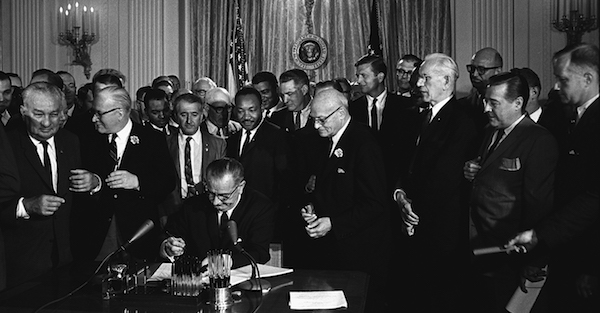 President Lyndon B. Johnson signs the 1964 Civil Rights Act as Martin Luther King Jr. and others watch on July 2, 1964. (Cecil Stoughton/White House Press Office via Wikimedia Commons)