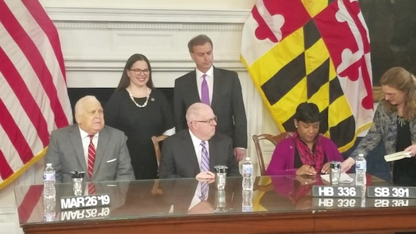 Maryland Del. Adrienne Jones (right) prepares to sign legislation into law for eligible federal workers in the state to receive unemployment benefits in the case of a federal government shutdown. Also present at the March 26 bill signing is (from left) Senate President Thomas V. Mike Miller Jr., Del. Jessica Feldmark, Gov. Larry Hogan and Sen. Brian Feldman. (William J. Ford/The Washington Informer)