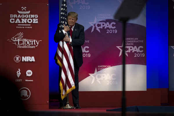 President Donald Trump hugs a U.S. flag as he takes the stage at CPAC in National Harbor, Maryland Saturday March 2, 2019. (Photo by J. Lawler Duggan/For The Washington Post via Getty Images)