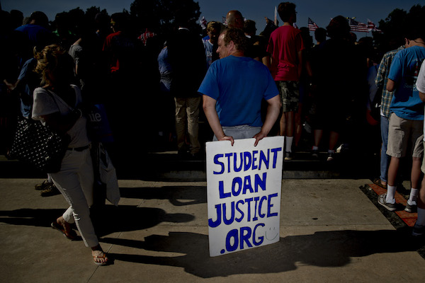 **FILE** An attendee holds a "Student Loan Justice" sign while waiting for Senator Bernie Sanders, an independent from Vermont and 2016 Democratic presidential candidate, to speak during campaign rally near Robert F. Kennedy Memorial Stadium in Washington, D.C., U.S., on Thursday, June 9, 2016. President Barack Obama formally endorsed Hillary Clinton to succeed him as the next U.S. president today in a bid to unify the party two days after she secured enough delegates to clinch the Democratic nomination. (Andrew Harrer/Bloomberg via Getty Images)