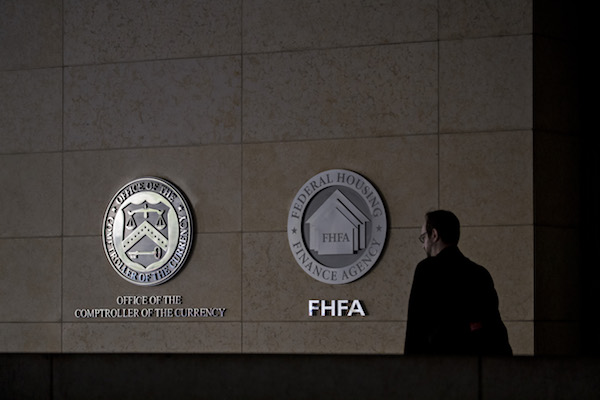 A pedestrian passes the seals of the Office of the Comptroller of the Currency (OCC) and Federal Housing Finance Agency (FHFA) at the organizations' headquarters in Washington, D.C., U.S., on Wednesday, March 20, 2019. The OCC this week fined Citibank $25 million for failing to offer some existing customers lower interest rates on mortgages or closing cost discounts that they were entitled to under a program for borrowers with a relationship with the bank. (Andrew Harrer/Bloomberg via Getty Images)