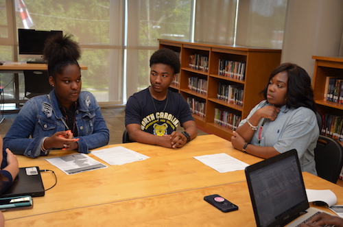 From left: H.D. Woodson freshman Natalia Givens and senior class valedictorian Tarrell Talbert discuss their progress using the D.C. Public Schools Student Guide to Graduation, College and Career with Damali Stewart, manager of postsecondary planning for D.C. Public Schools and a former Woodson counselor. (Anthony Tilghman/The Washington Informer)
