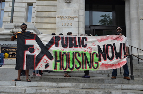Ahead of the D.C. Council vote on May 28, protesters hold a sign on the steps of the John A. Wilson Building. (Anthony Tilghman/The Washington Informer)