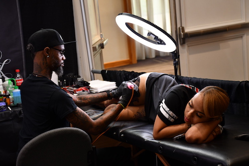 Tattoo artist Tro of Black Ink Atlanta giving a tattoo session to an attendee at the DC Tattoo Arts Expo held at the Crystal Gateway Marriott in Arlington, Va., from May 31 to June 2. (Anthony Tilghman/The Washington Informer)
