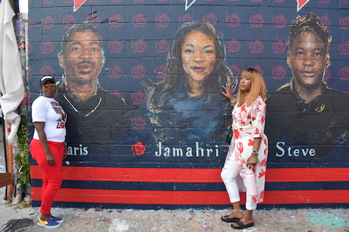 Seditra Brown stands by a portrait of her son Paris Brown as Q Wallace stands next to an image of her daughter Jamahri Sydnor. (Anthony Tilghman/The Washington Informer)
