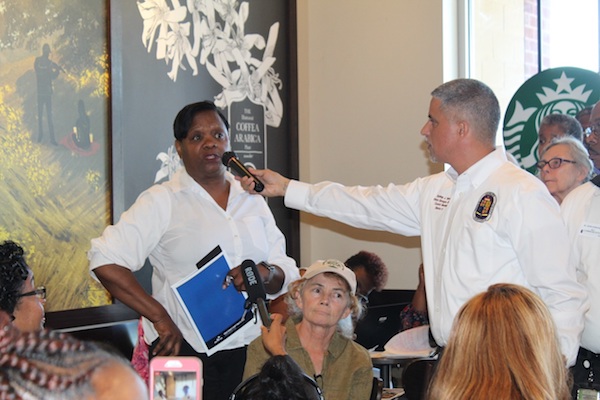 Prince George's County Councilman Sydney Harrison holds a microphone for a woman as she asks a question during an Aug. 29 discussion forum on education at a Starbucks in Clinton. (Brigette White/The Washington Informer)