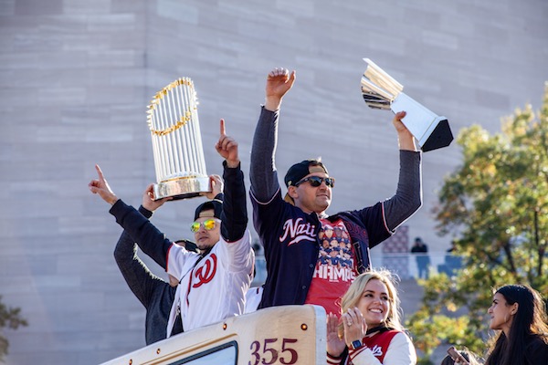 Washington Nationals first baseman Ryan Zimmerman (right) holds the National League Championship trophy with his wife seated by his side and the Nationals general manager Mike Rizzo hoists the World Series trophy during the Nationals' parade Nov. 2 in northwest D.C. (Ja’Mon Jackson/The Washington Informer)