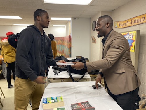 Entrepreneur and former NFL cornerback Vontae Davis gives a copy of his new children's book to Derrick Lewis during College Bound Inc.'s weekly academic mentoring session at Walker Memorial Baptist Church in northwest D.C. on Nov. 14. (Courtesy of Kenneth Ward)