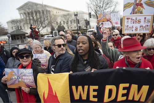 Joaquin Phoenix (center) and Dr. Omekongo Dibinga march Jan. 10 against the war in Iran at a rally where notably only a few African Americans attended. (Anthony Tilghman/The Washington Informer)