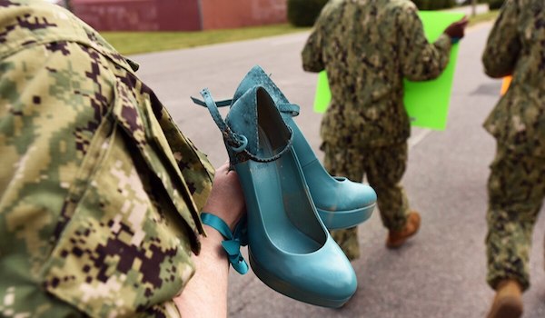 A sailor from Navy Expeditionary Combat Command carries a pair of shoes, painted teal to symbolize victims of sexual assault, as she participates in the "Walk a Mile in Their Shoes" command event at Joint Expeditionary Base Little Creek on Aug. 25. (Mass Communication Specialist 3rd Class Lisa Reese/Navy via Military Times)