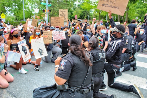 Police officers from the Montgomery County’s 2nd District take a knee with protestors during a peaceful protest in Bethesda, Maryland, on June 2 against racism and police brutality. (Brigette Squire/The Washington Informer)