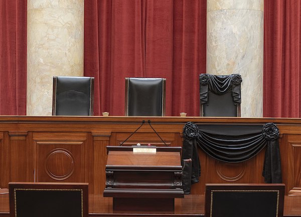 The courtroom of the Supreme Court showing Associate Justice Ruth Bader Ginsburg’s Bench Chair and the Bench in front of her seat draped in black following her death on Sept. 18, 2020. (Fred Schilling/Collection of the Supreme Court of the United States)