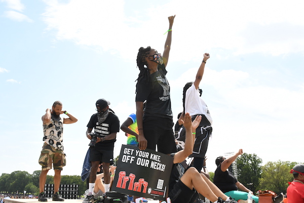 Protesters stand atop a stoop at the Lincoln Memorial in Washington with raised fists during the Commitment March on Aug. 28. (Roy Lewis/The Washington Informer)