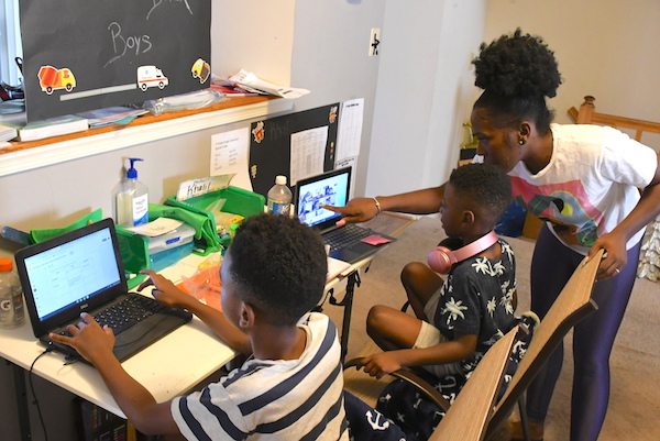 Angel Johnson, 33, helps her two elementary school aged sons, Asahai and Khalil, with schoolwork during their virtual learning class work. (Roy Lewis/The Washington Informer)
