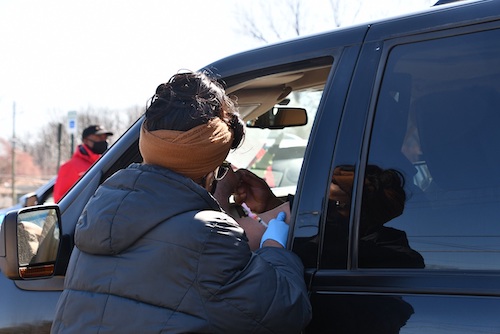A District Heights, Maryland, resident sitting inside a vehicle prepares to receive a coronavirus vaccine during a drive-thru community clinic outside First Baptist Church of District Heights on March 20. (Anthony Tilghman/The Washington Informer)