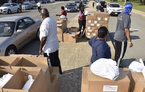 Volunteers prepare to put bags and boxes of food in vehicles at a Sept. 11 distribution giveaway by Kingdom Fellowship AME Church at High Point High School in Beltsville. (Robert R. Roberts/The Washington Informer)