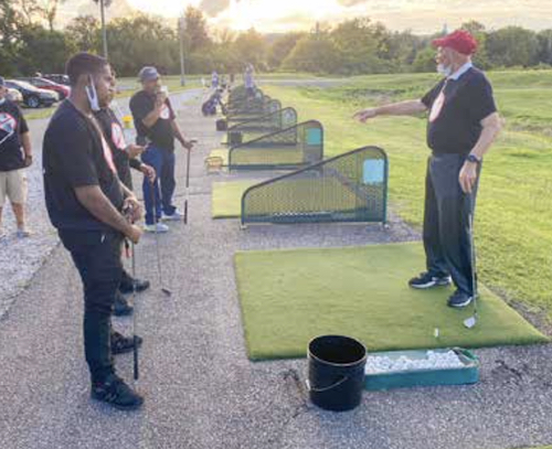 Ray Savoy, Langston Golf Course instructor, gives everyone at the "Clubs Not Guns" bi-weekly event, held throughout the month of August, a lesson on holding golf clubs. (Rob Warren/The Washington Informer)