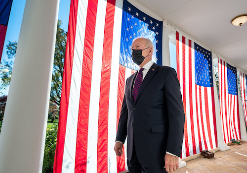 **FILE** President Joe Biden walks past draped America flags along the Colonnade of the White House, Monday, November 15, 2021, en route to sign the Infrastructure Investment and Jobs Act. (Official White House Photo by Adam Schultz)
