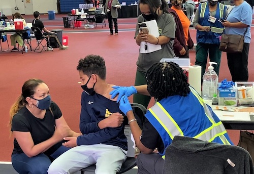 **FILE** Christopher Martin, 12, talks with his mother, Tara Moore (left) as he receives a coronavirus vaccine in Landover, Maryland, on May 14. (William J. Ford/The Washington Informer)