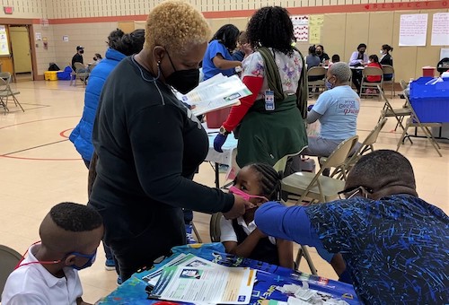 Miracle Epps, 5, receives a coronavirus vaccine at a clinic inside Judge Sylvania Woods Elementary in Glenarden, Maryland, on Nov. 8 as her brother Emmanuel Jones (left), 6, who got his shot earlier, looks on. (Robert R. Roberts/The Washington Informer)