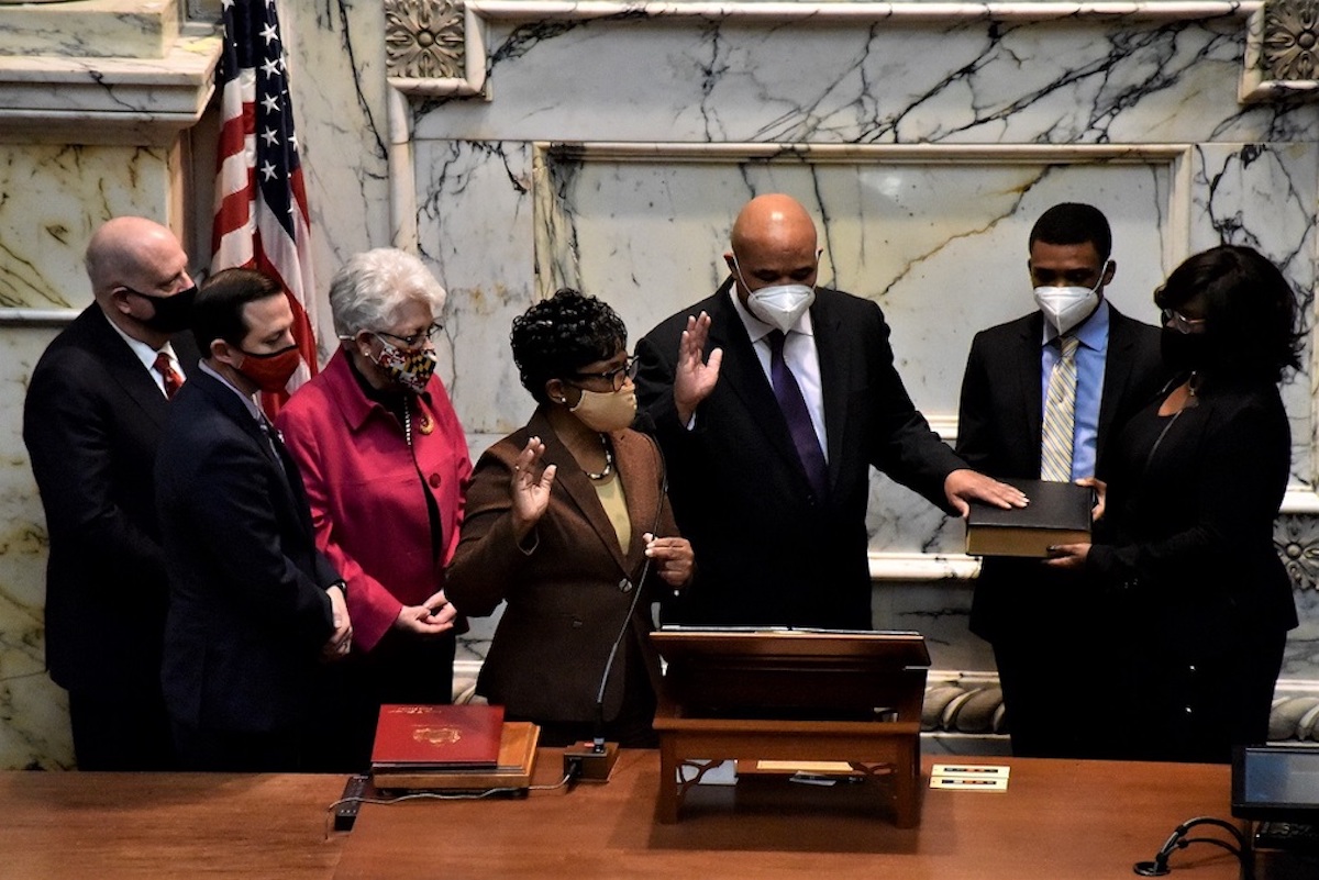 Former Del. Dereck Davis places his left hand on a Bible as he reads the oath to become Maryland's 24th treasurer on Dec. 17. House Speaker Adrienne Jones (left) presided. Davis was joined by his wife, Monique (right) and their son Dereck Davis Jr. (Robert R. Roberts/The Washington Informer)