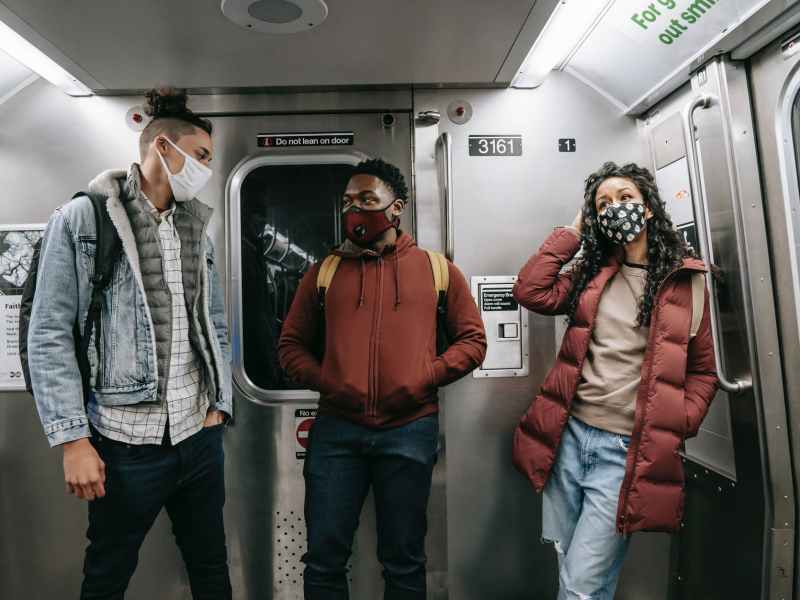 unrecognizable multiethnic friends in masks standing in subway train