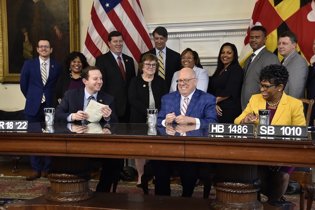 Maryland Gov. Larry Hogan (center) smiles alongside Senate President Bill Ferguson (left), House Speaker Adrienne Jones (right) and other lawmakers after the three state leaders signed legislation into law to suspend the state’s gas tax for 30 days on March 18. (Robert R. Roberts/The Washington Informer)