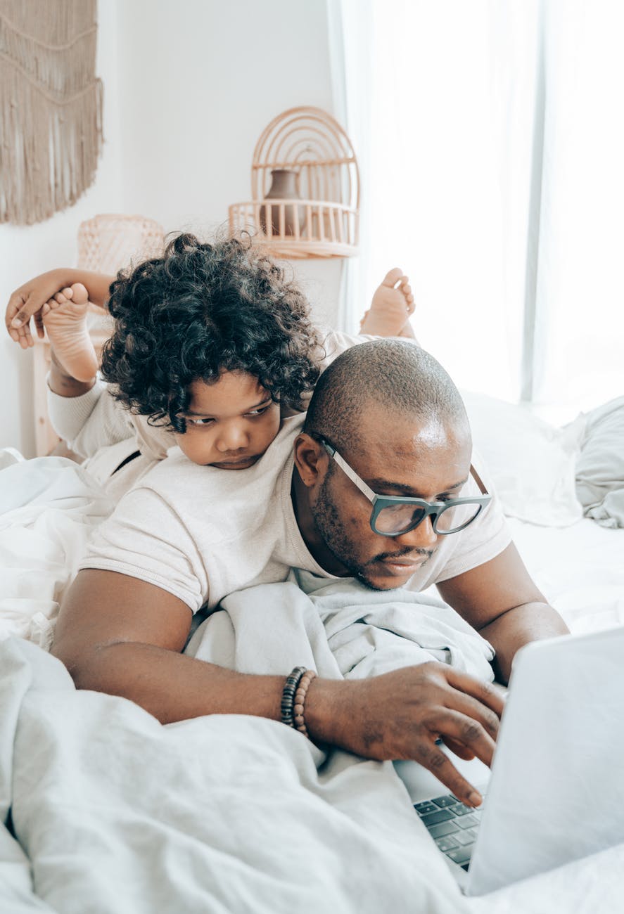 father working from home with child on his back