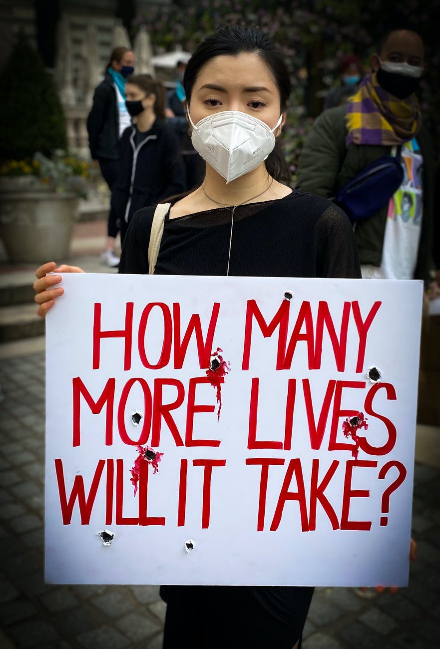 woman in black jacket holding white and red happy birthday signage