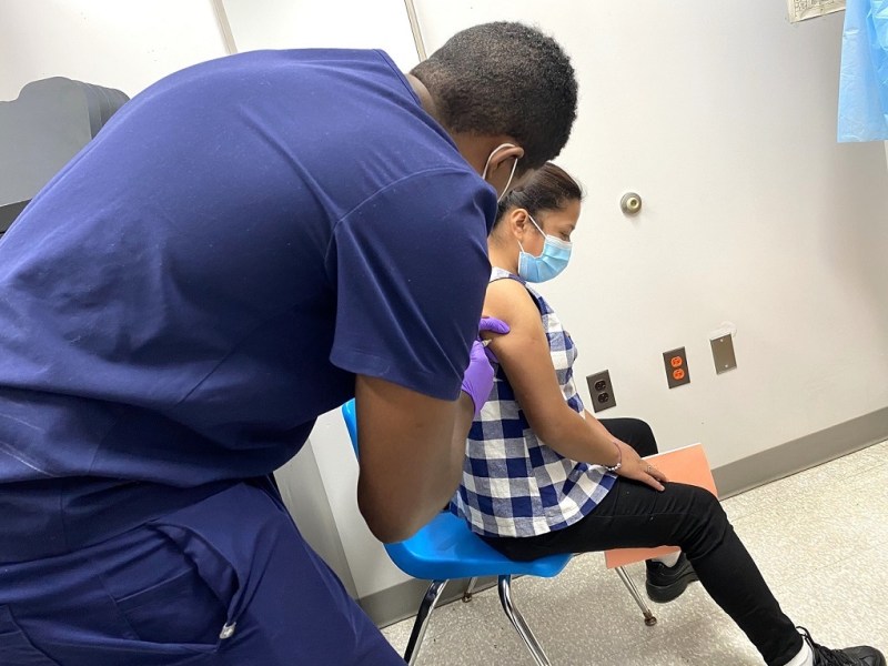 Marylin Clarisa Pérez Suy (right), 17, receives one of four shots in her right arm at a free immunization clinic at Northwestern High School in Hyattsville, Maryland, on Aug. 22. Marylin, who also got shots in her left arm, recently moved to Prince George's County from Guatemala in Central America. (William J. Ford/The Washington Informer)