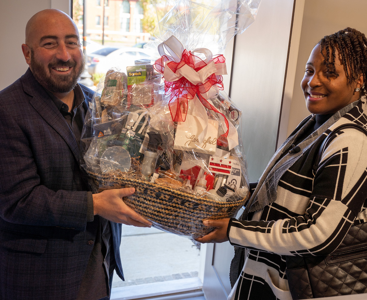 John Falcicchio, D.C. Deputy Mayor for Planning and Economic Development, presents Brittany Freeman with a congratulatory gift basket after she closed on her new home in southeast D.C. (Marckell Williams/The Washington Informer)