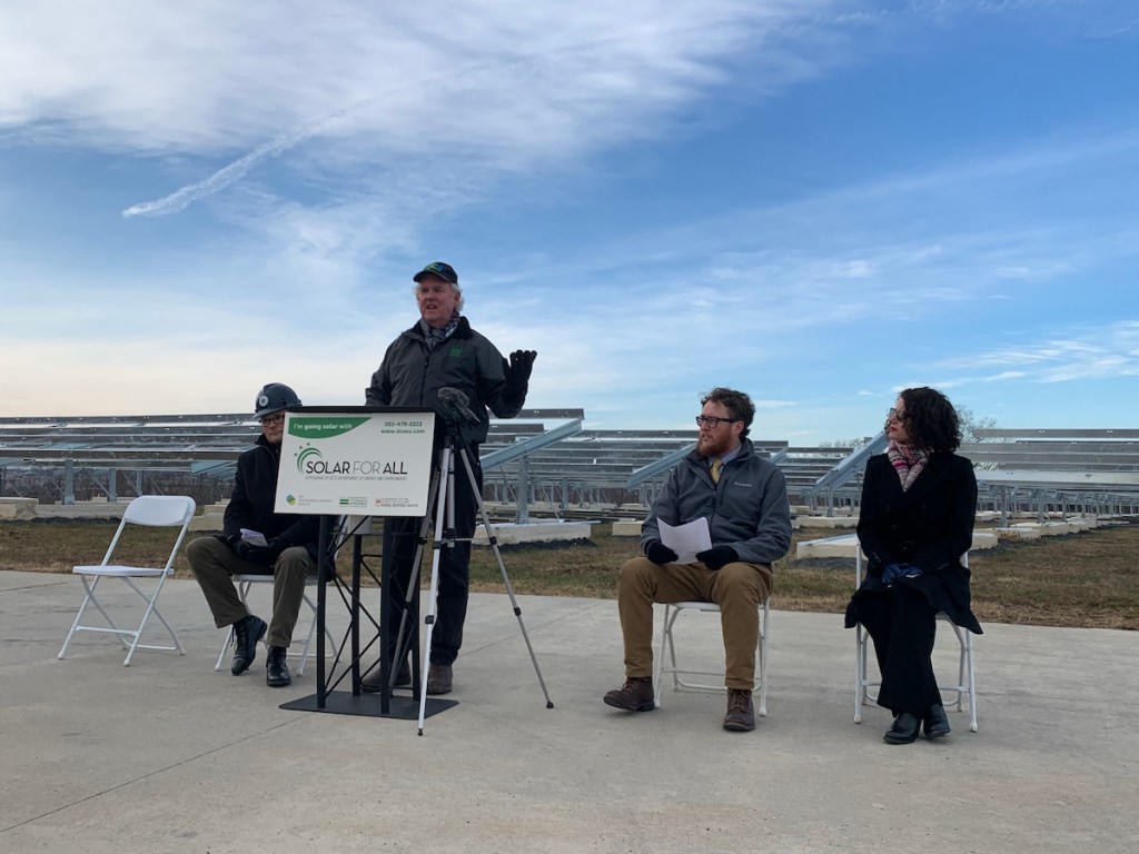 Department of Energy and Environment Director Tommy Wells speaks in front of rows of frames waiting to hold solar panels once long-delayed materials arrive. (Kayla Benjamin/The Washington Informer)