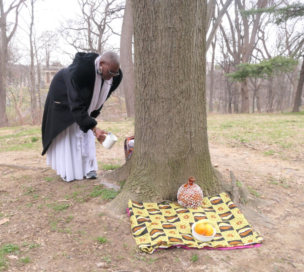 During a Feb. 20 ceremony at the Mount Zion-Female Union Band Society Cemetery, Nana Malaya Rucker-Oparabea leads visitors in the pouring of libation and veneration of ancestors. (Shevry Lassiter/The Washington Informer)