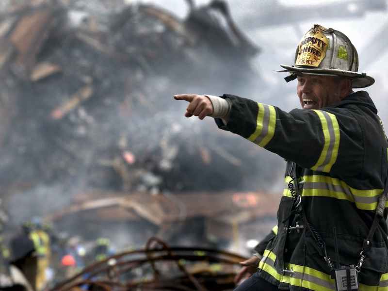 fire fighter wearing black and yellow uniform pointing for something