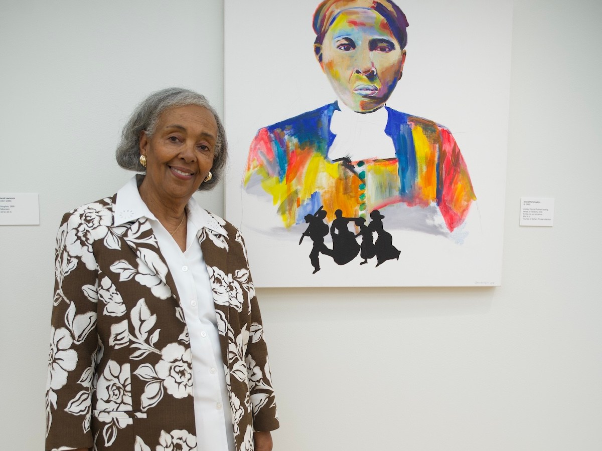 Patricia Turner Walters, with a Harriet Tubman painting by Jessica Marie Hopkins, a Howard University alumna, is in the exhibition “Genesis: The African American Experience in Art,” cur- rently at the Howard University Gallery of Art. (Marckell Williams/The Washington Informer)