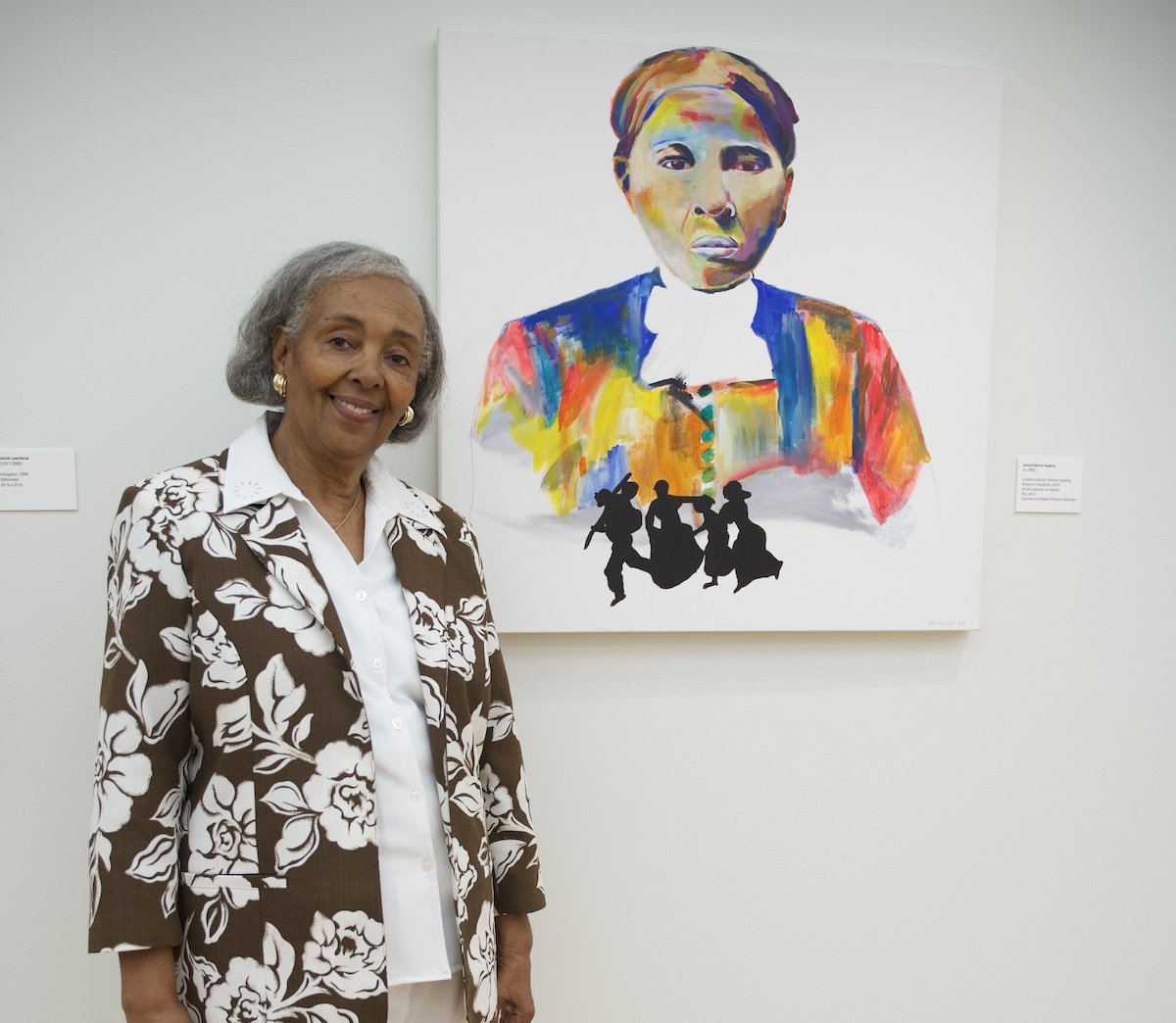Patricia Turner Walters, with a Harriet Tubman painting by Jessica Marie Hopkins, a Howard University alumna, is in the exhibition “Genesis: The African American Experience in Art,” cur- rently at the Howard University Gallery of Art. (Marckell Williams/The Washington Informer)