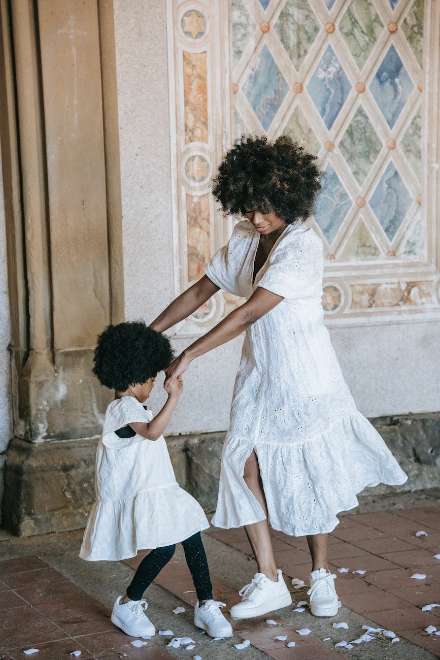 a woman and a child in white dresses dancing on the floor with scattered petals